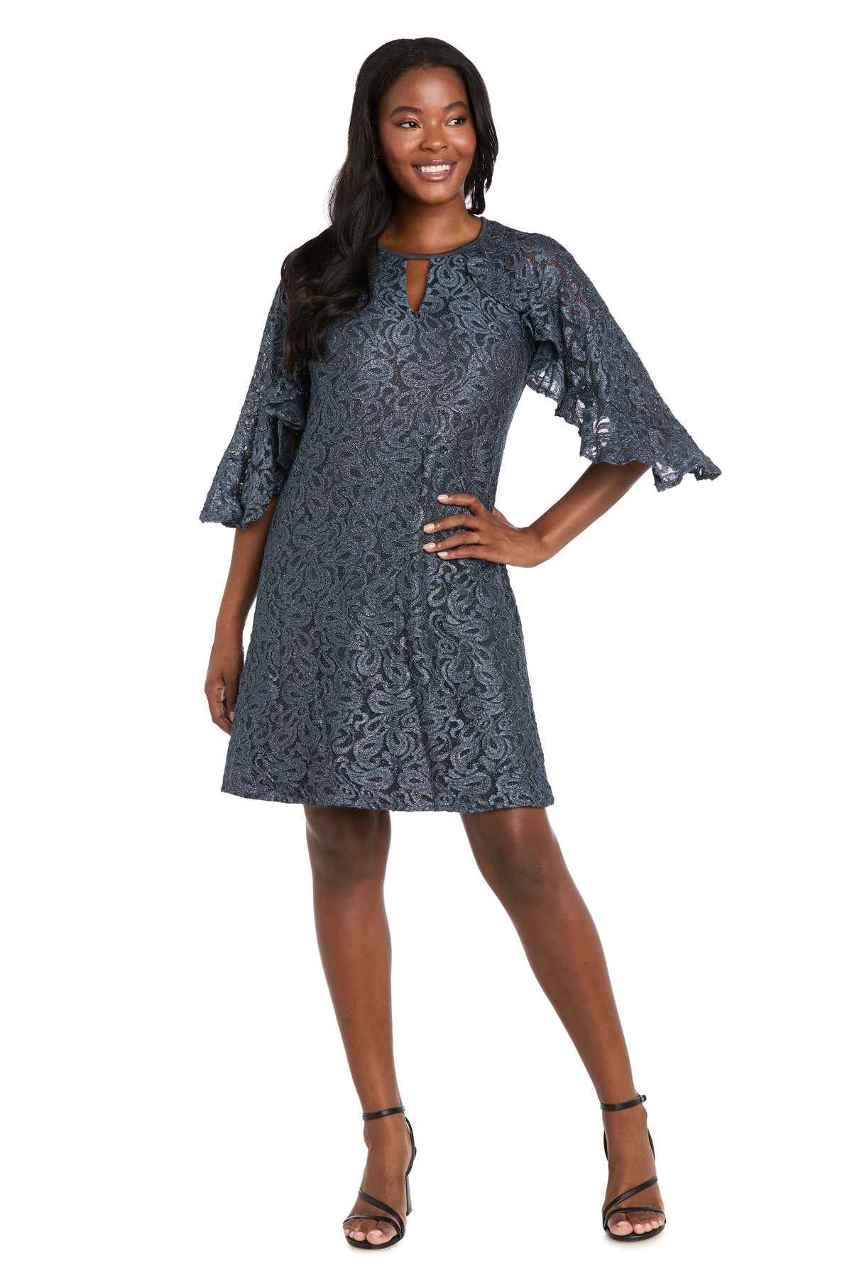 Woman modeling the R&M Richards 4226 Short Lace Semi-Formal Dress, knee-length with flared sleeves, a small front keyhole, and an elegant A-line silhouette. She stands smiling with one hand on her hip.